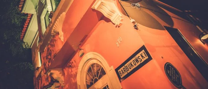 Bar Bukowski, um icônico reduto da boemia carioca, com ambiente vibrante, luzes neon, pôsteres de rock e literatura, e frequentadores imersos em conversas e música ao vivo.